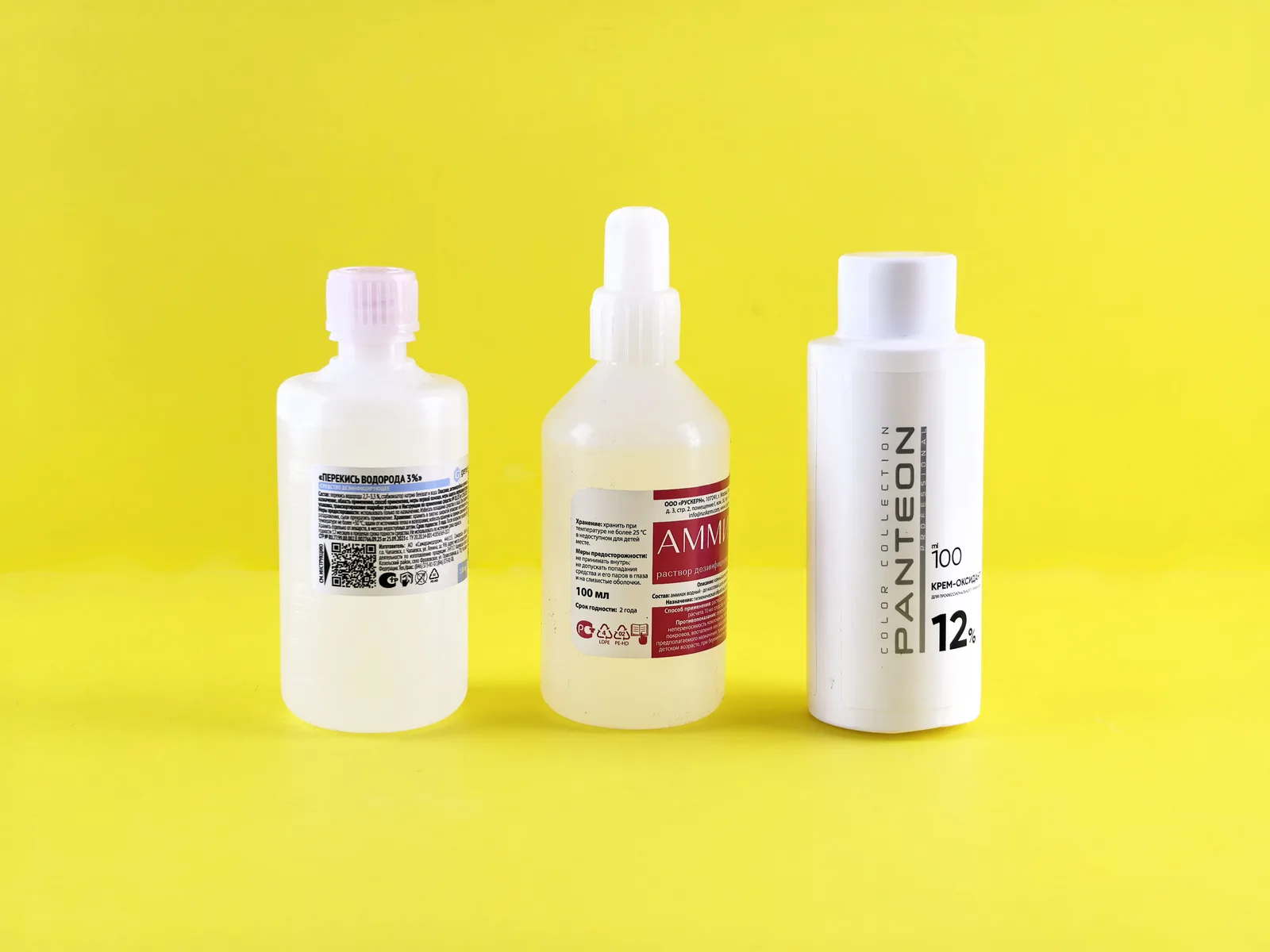 Three bottles with labels on a vibrant yellow surface emphasizing chemical substances. How to Mix Pressure Washing Chemicals for Concrete and Vinyl
