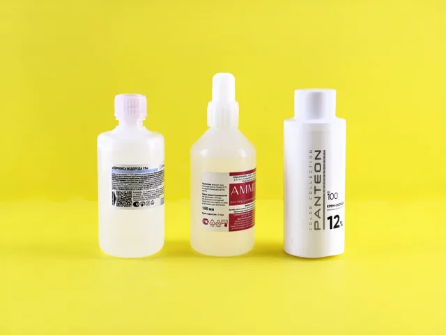 Three bottles with labels on a vibrant yellow surface emphasizing chemical substances. How to Mix Pressure Washing Chemicals for Concrete and Vinyl