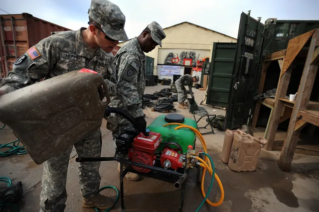 U.S. Army Staff Sgt. Jonathan Herring of Augusta, Ga., (left) fills a pressure washer with fuel as Spc. Robert Scott, of Brooklyn, N.Y., steadies the nozzle, both Soldiers are assigned to 185th Military Intelligence Company, 2nd Stryker Brigade Combat Team, 25th Infantry Division, Multi-National Div. How work flows through a pressure washing business for a small operation