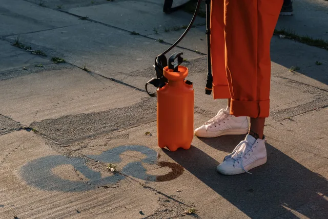 A person in orange pants using an orange sprayer on concrete pavement. 9 lessons worth learning about pressure washing services